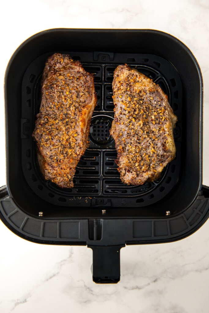 Cooked steaks in the air fryer basket.