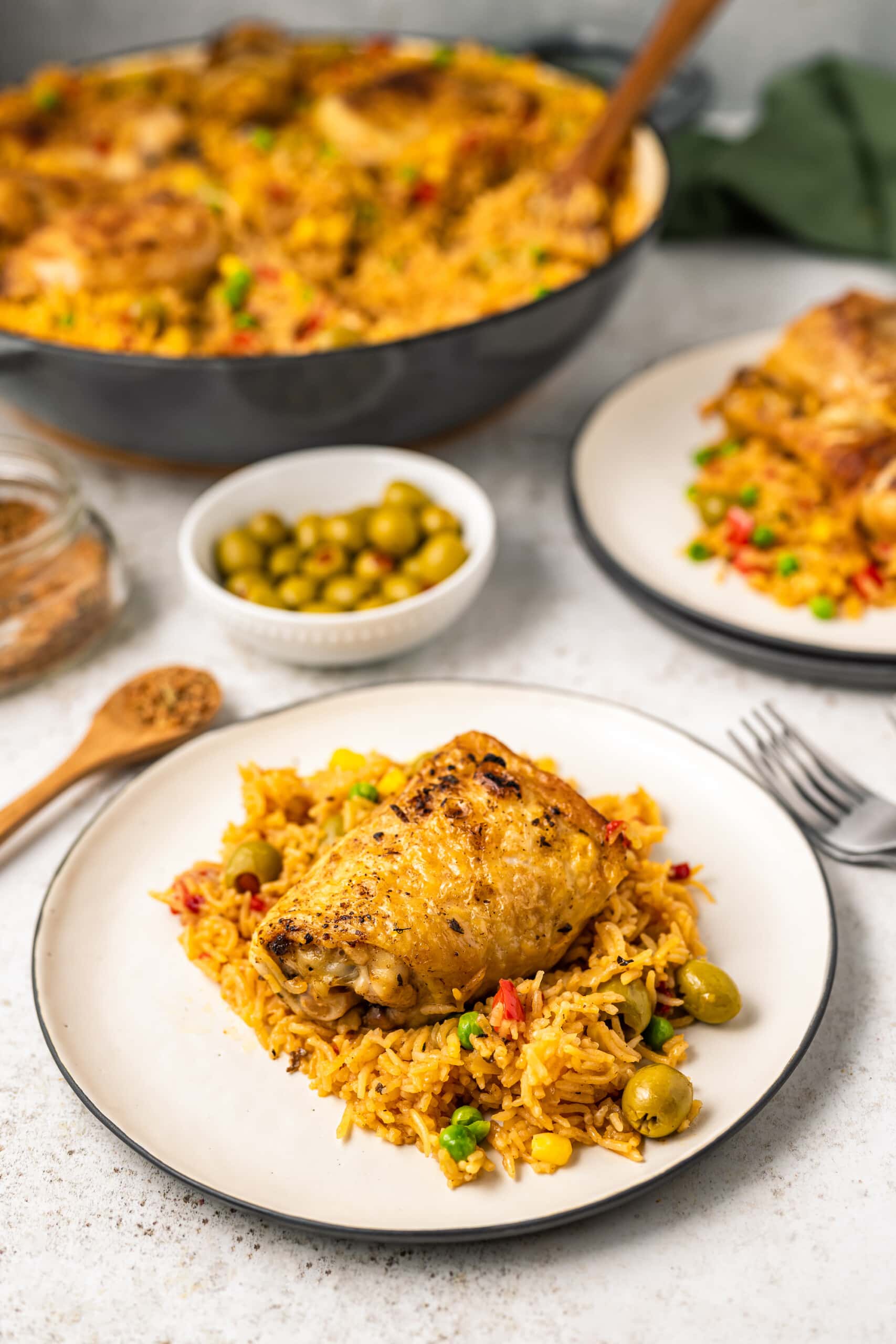 A plate of arroz con pollo in the foreground with the rest of the pot in the background.