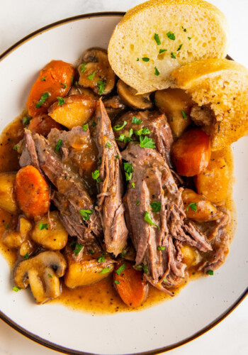 Close up of a bowl of crockpot pot roast with bread.