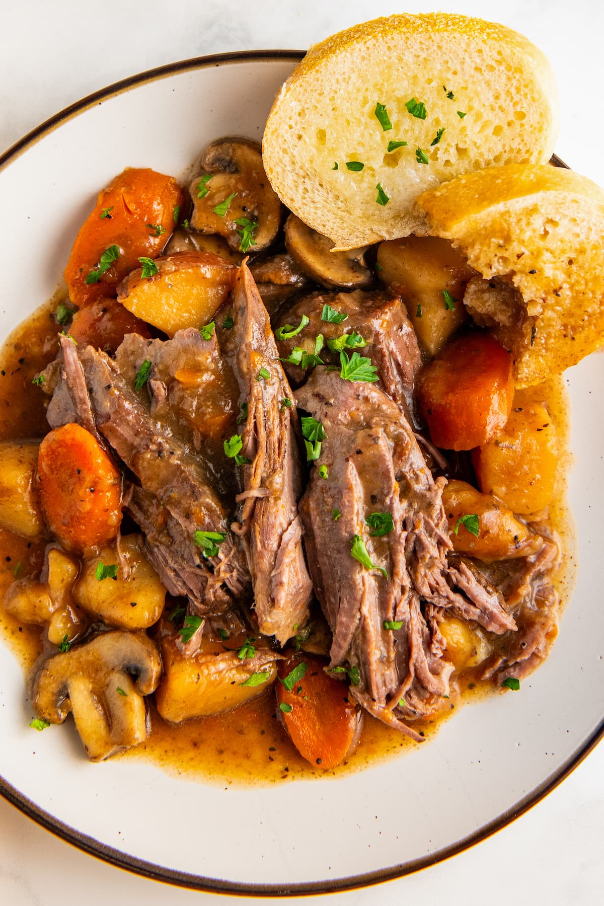 Close up of a bowl of crockpot pot roast with bread.