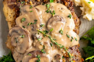 Mushroom sauce on top of steak with a side of potatoes.