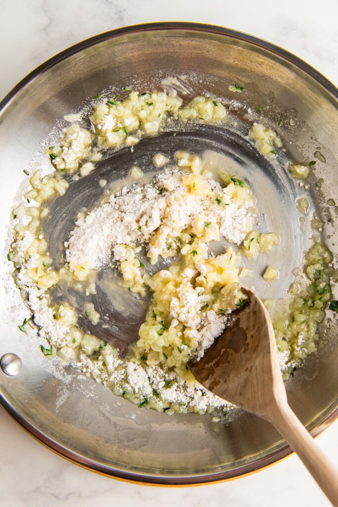 Stirring in flour with sautéed garlic and herbs.