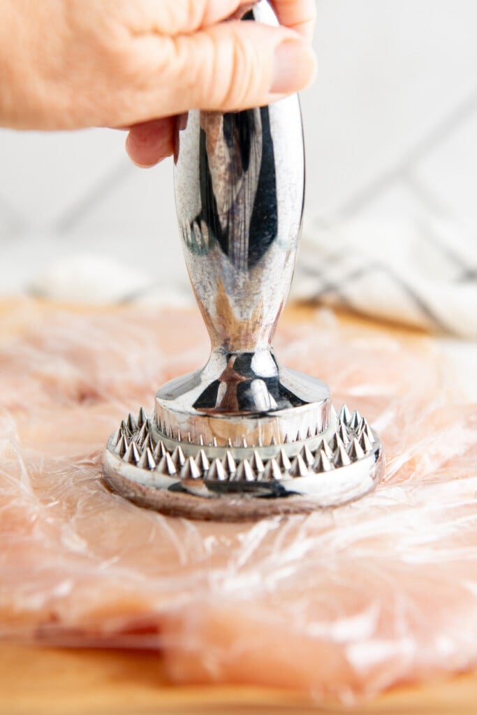 Using a meat tenderizer to pound out chicken breasts.