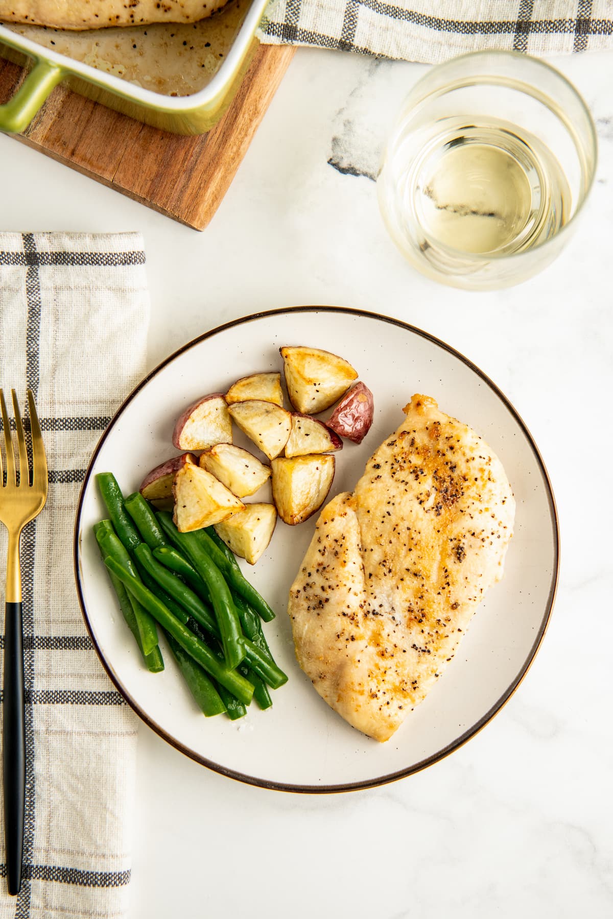 Chicken on a plate with roasted potatoes and green beans.