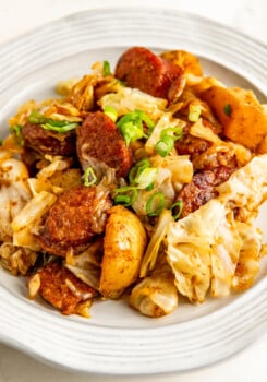 Cabbage, sausage, and potatoes on a white plate.