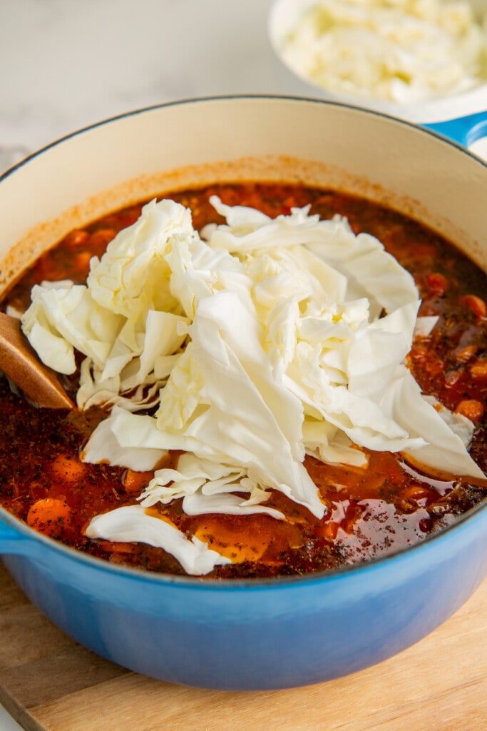 Adding chopped cabbage to the soup.