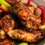 Cajun wings in a bowl with fresh carrots, celery and radishes.