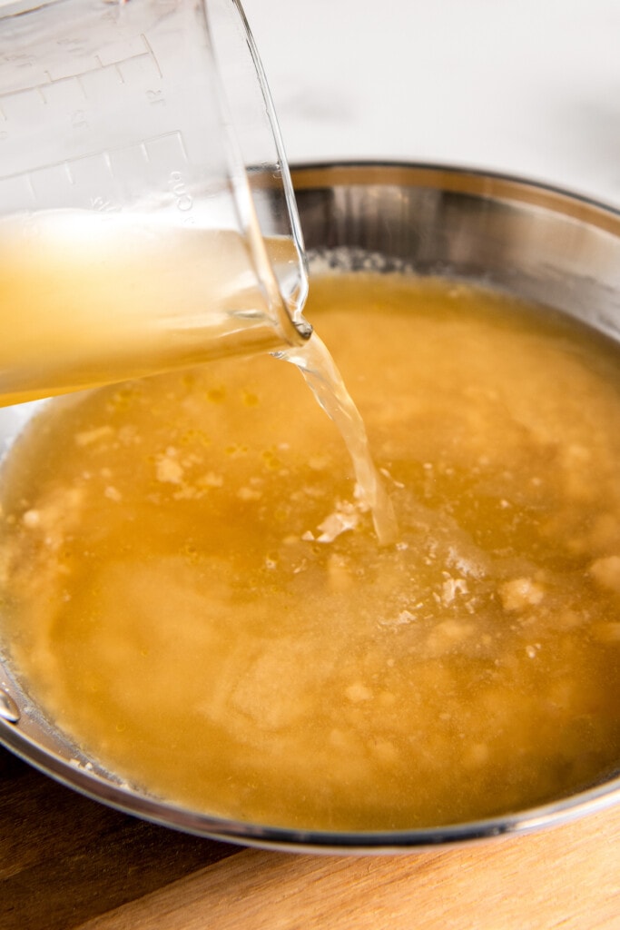 Pouring chicken stock into the pan.