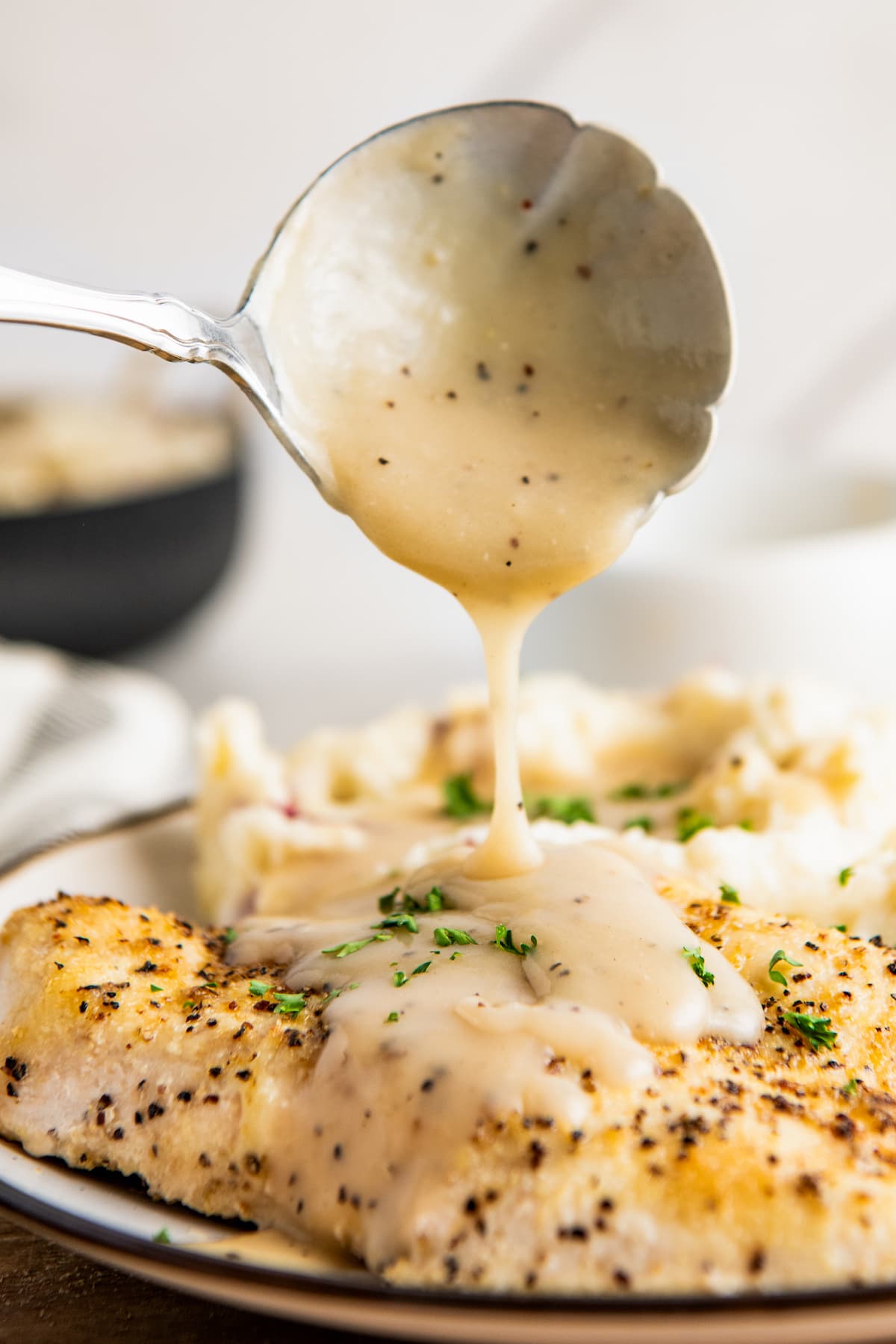 Spooning gravy over a piece of chicken.