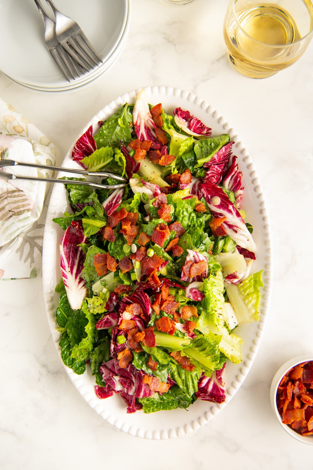 A white serving plate with wilted lettuce salad.