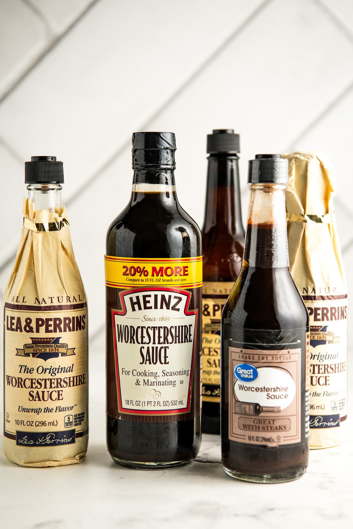 Different brands of Worcestershire sauce arranged on a countertop.