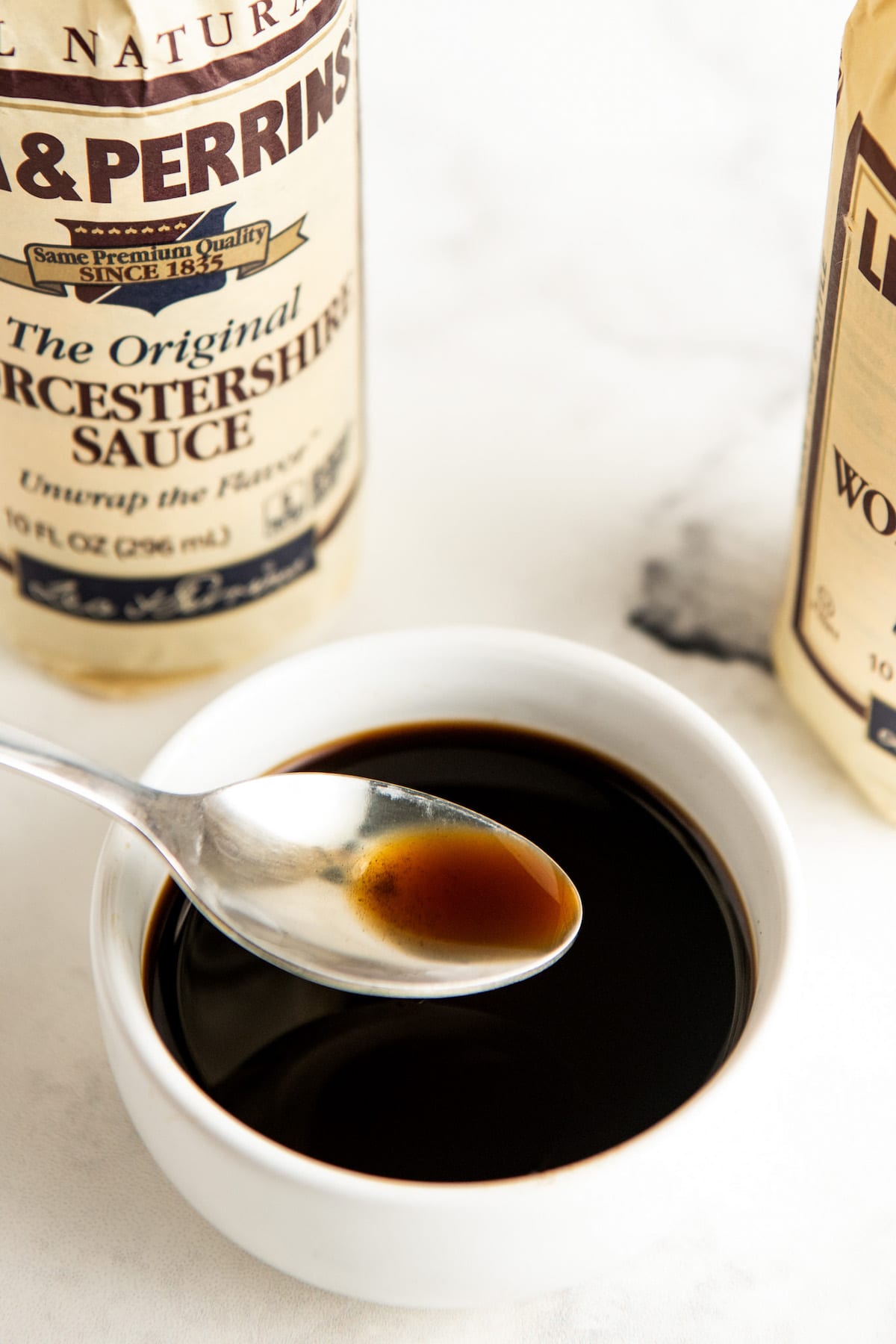 A bowl full of Worcestershire sauce with a spoon scooping some out.