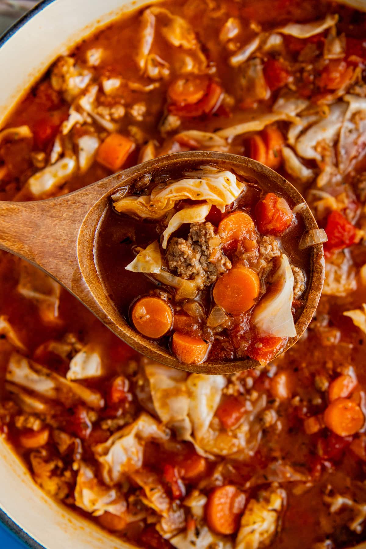 A pot of beef and cabbage soup with a ladle scooping out a serving.