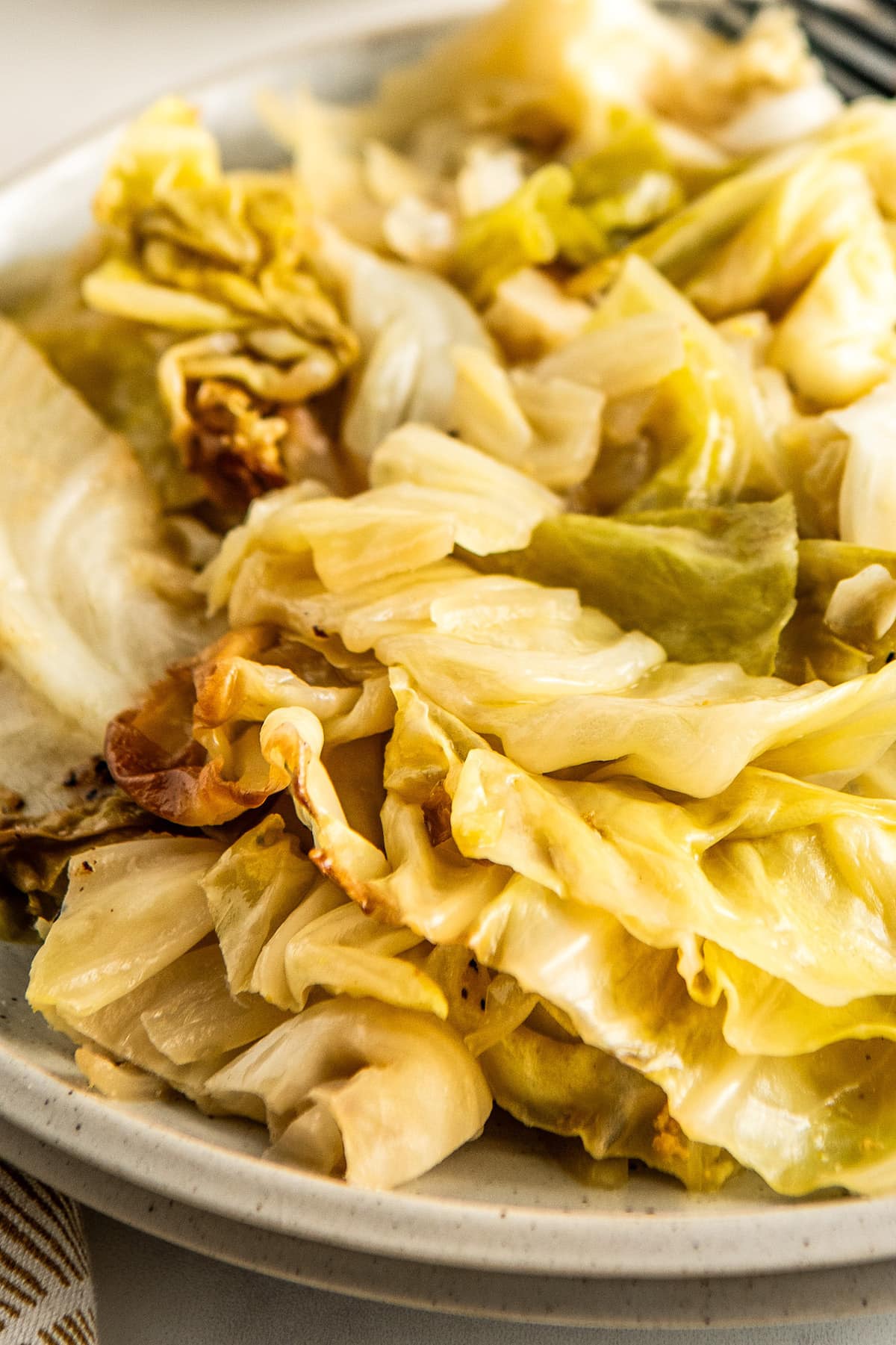 Tender and buttery crockpot cabbage  with onions served on a plate. 