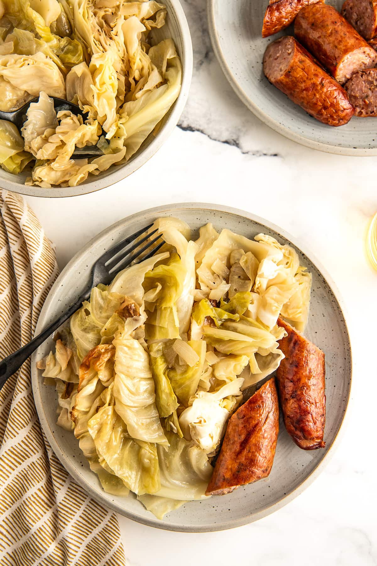A plate of sausage and cooked cabbage.