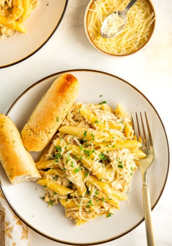 A plate of chicken Alfredo with bread.
