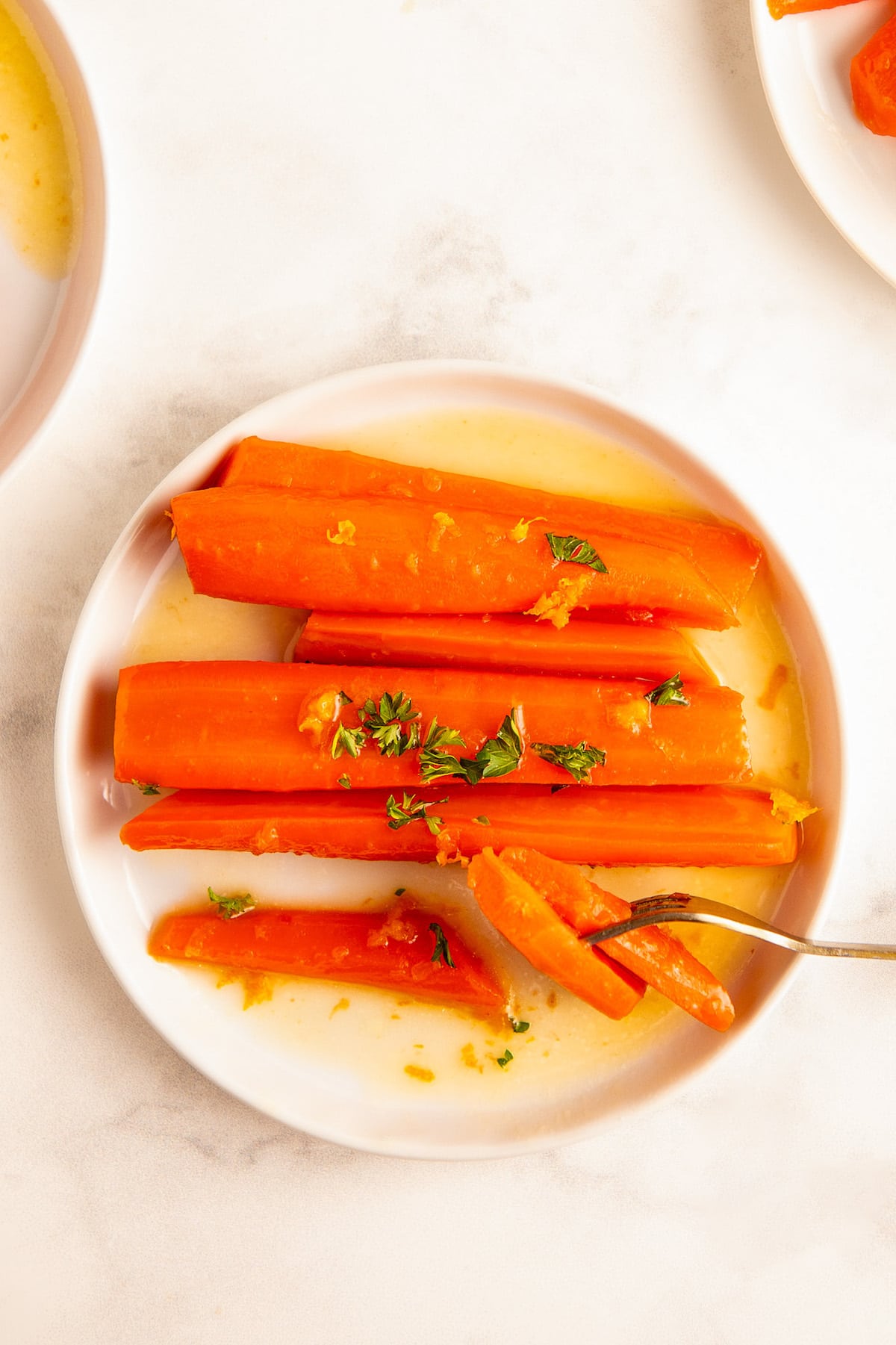 A white plate full of sweet and tender honey glazed carrots.