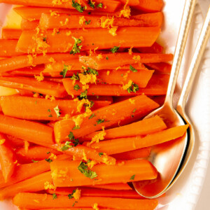 Glazed carrots garnished with orange zest and fresh herbs.