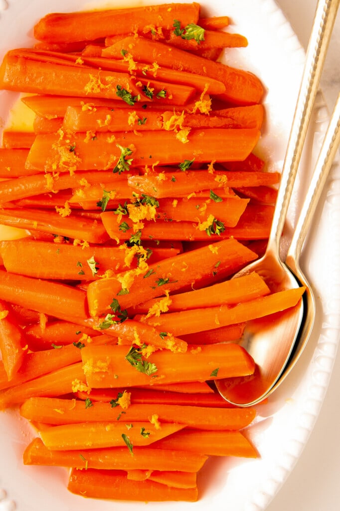 Glazed carrots garnished with orange zest and fresh herbs.