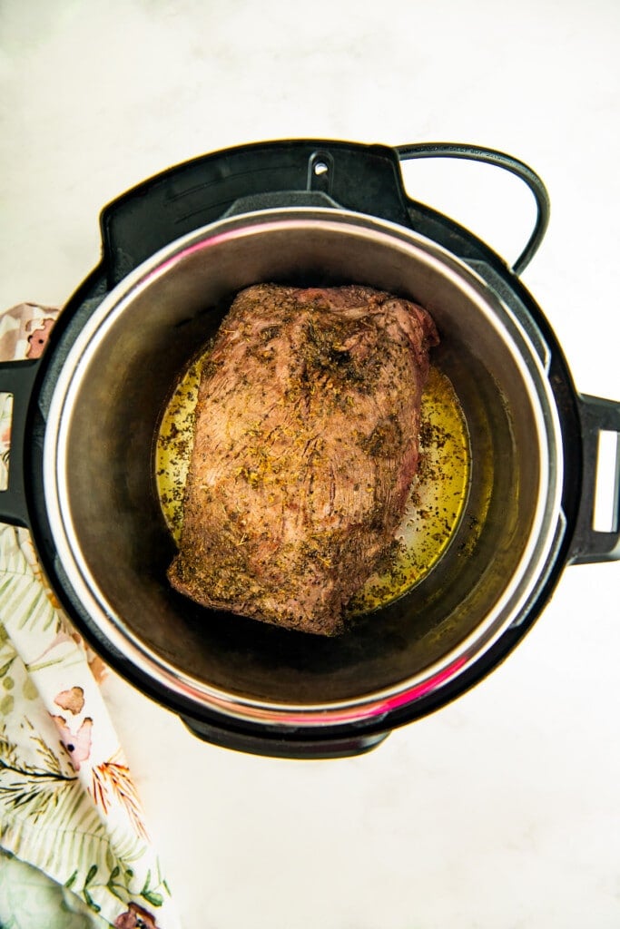 Searing the chuck roast on each side in the instant pot.