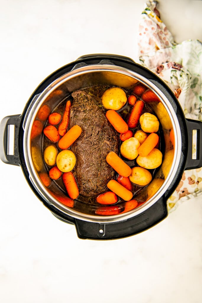 A chuck roast, carrots, and potatoes in the intant pot ready to cook.