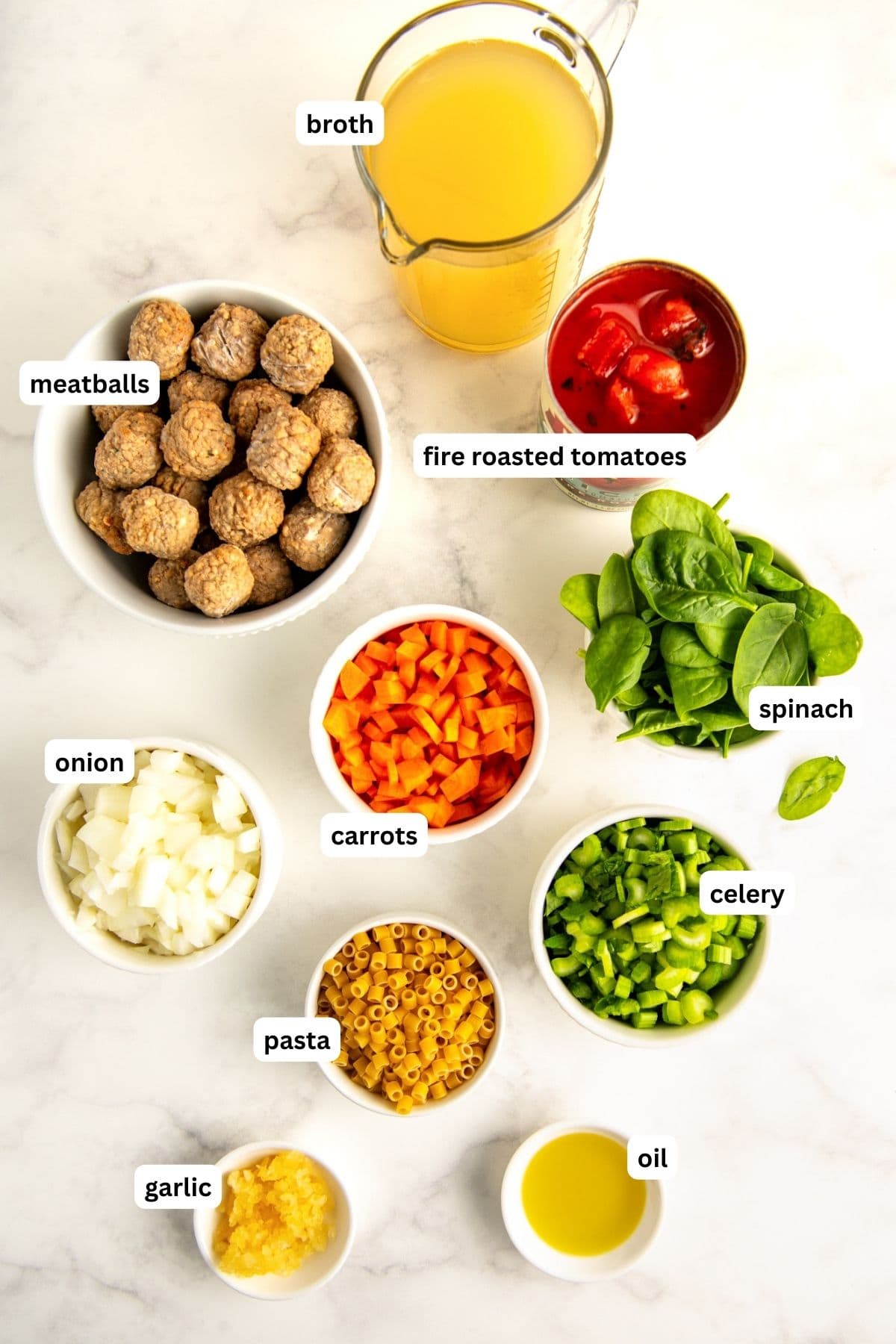 Ingredients for Italian wedding soup recipe arranged in bowls, from top to bottom: broth, meatballs, fire roasted tomatoes, spinach, onion, carrots, celery, pasta, garlic and oil.