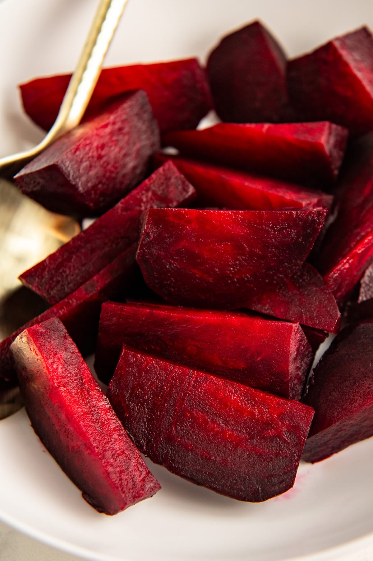 Cut up beets on a white plate.