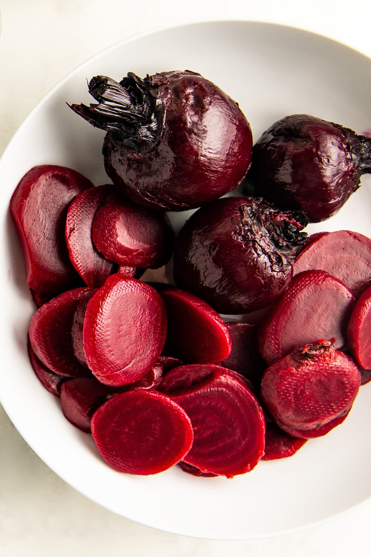 Whole and sliced beets on a white plate.