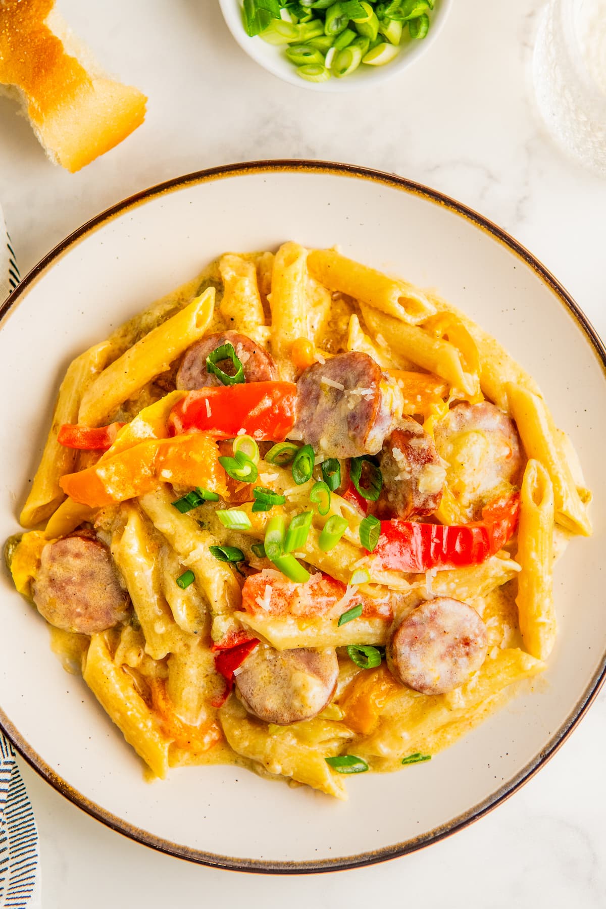 A plate of creamy Cajun sausage pasta with colorful bell peppers.