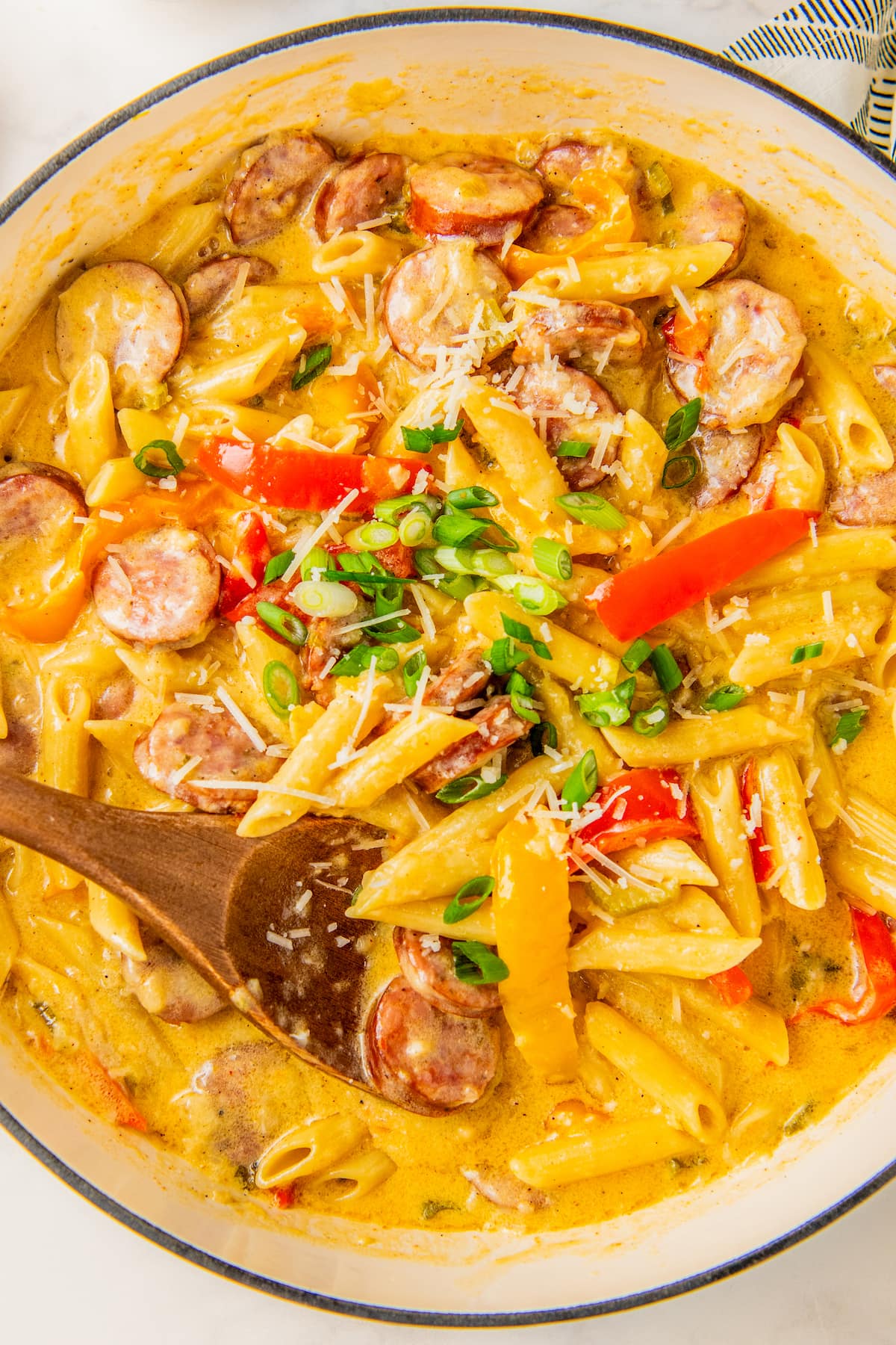 Creamy Cajun sausage pasta garnished with parmesan and green onions.