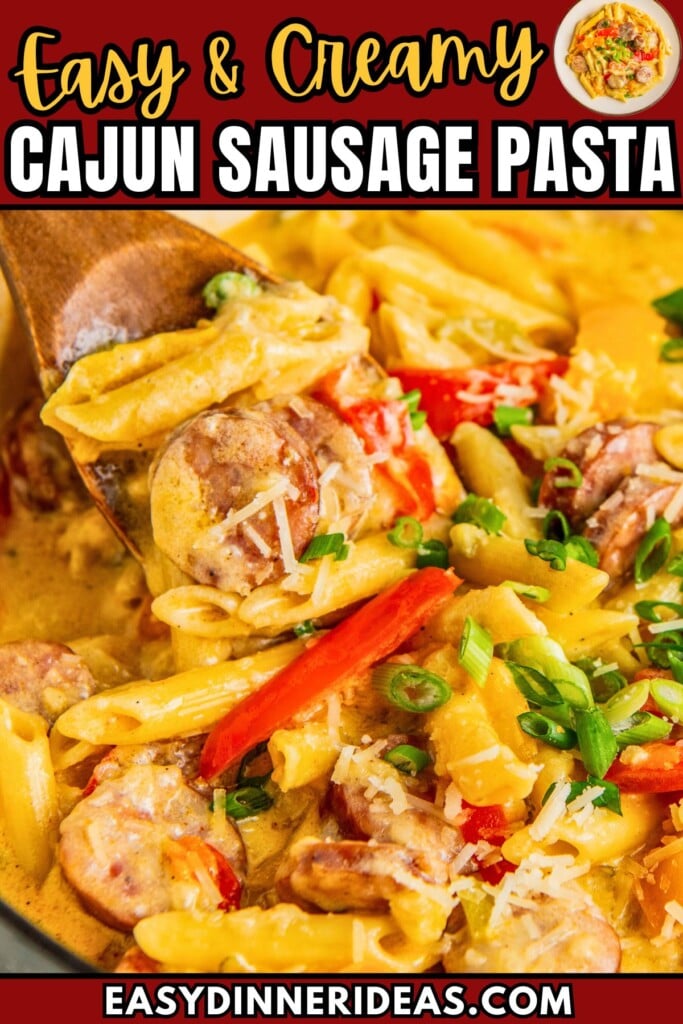 Creamy and cheesy Cajun sausage pasta in a skillet with a wooden spoon scooping out a serving.
