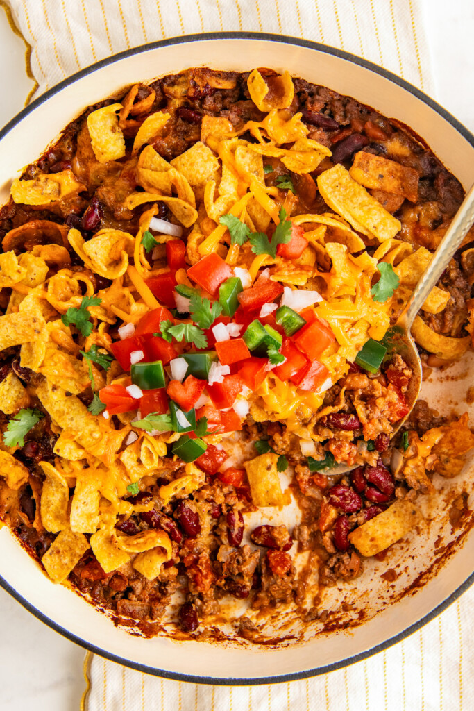 Close up of garnished Frito pie in a large Dutch oven.