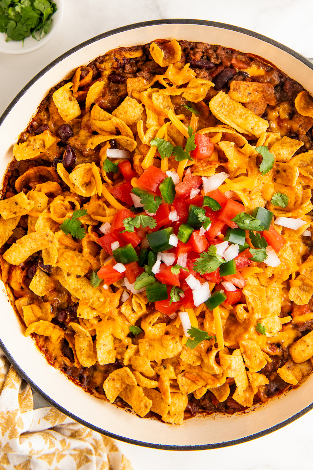 Hearty and beefy Frito pie with lots of melty cheese in a skillet.