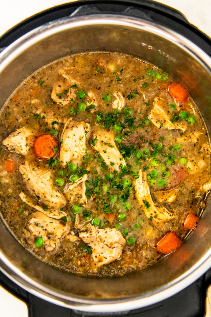 Cooked chicken stew with fresh herbs on top in the instant pot.
