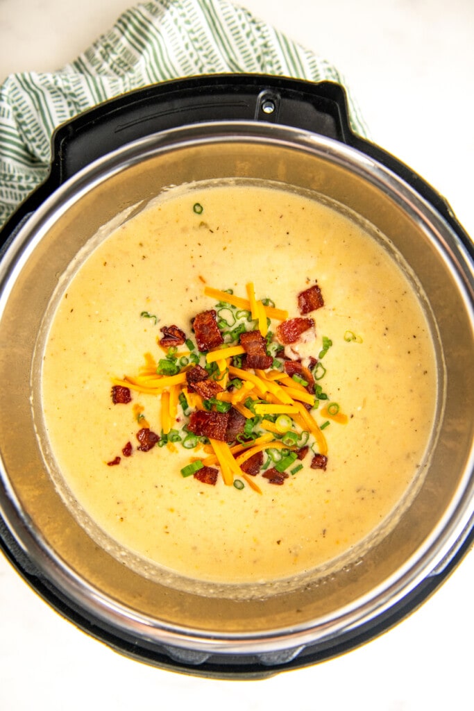 Cooked instant pot baked potato soup with bacon, cheese, and chives on top.