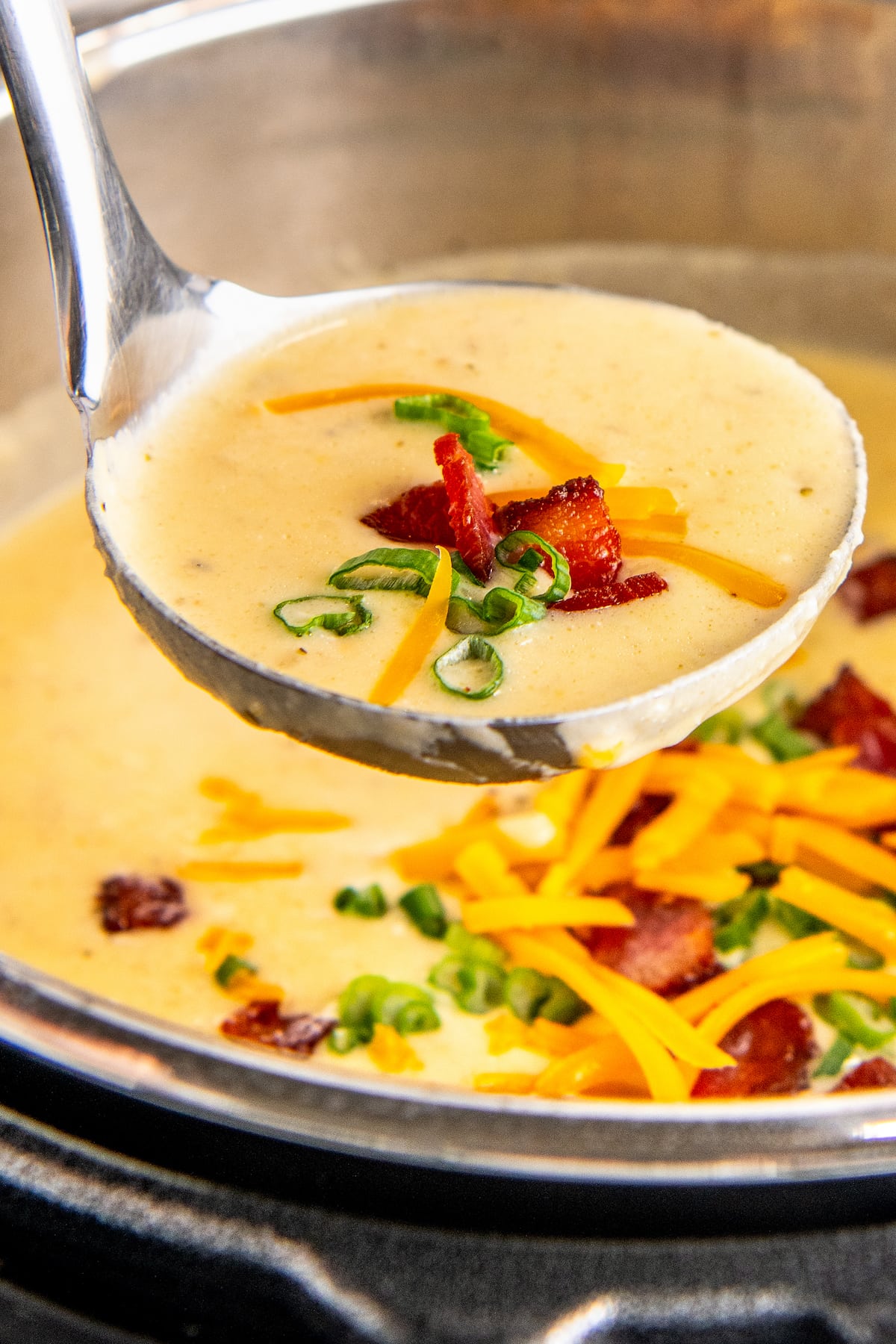 Ladling out a spoonful of smooth and creamy instant pot potato soup loaded with cheese, bacon and more.