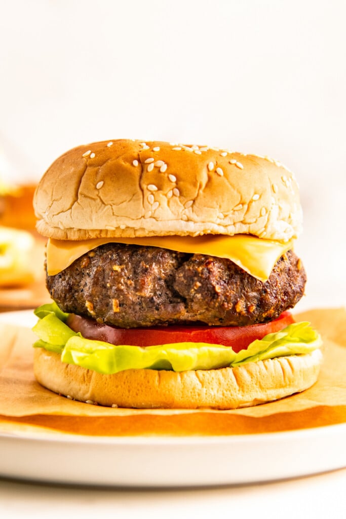 An air fryer hamburger with all the fixings on a wooden cutting board.