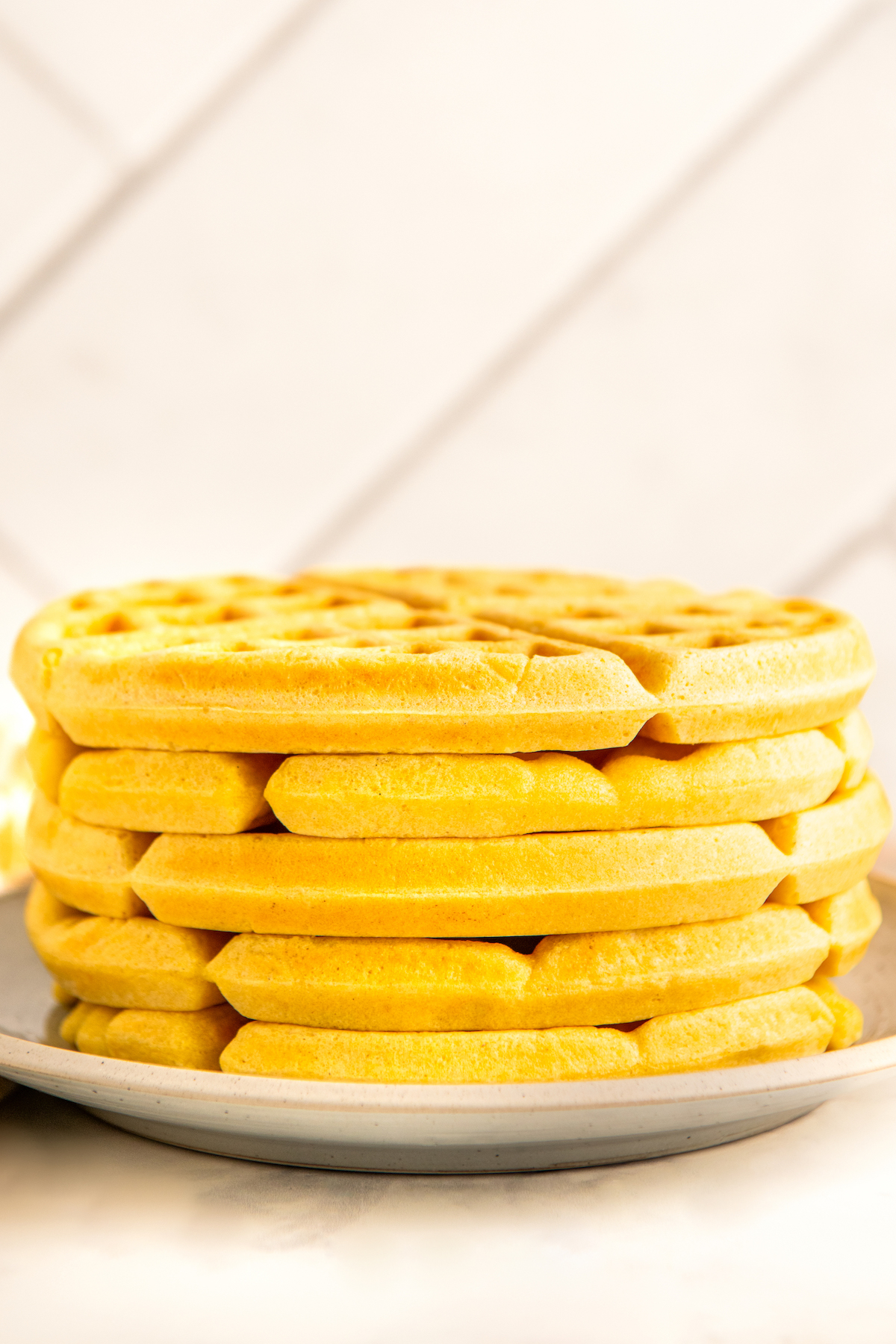 A stack of sweet and savory cornmeal waffles with crispy edges. 