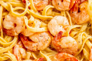 Creamy lemon garlic shrimp pasta in a skillet with juicy and buttery shrimp and fettuccine noodles in a parmesan cream sauce.