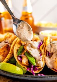 Adding creamy chipotle sauce to some tacos.
