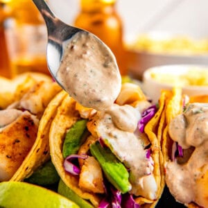 Adding creamy chipotle sauce to some tacos.