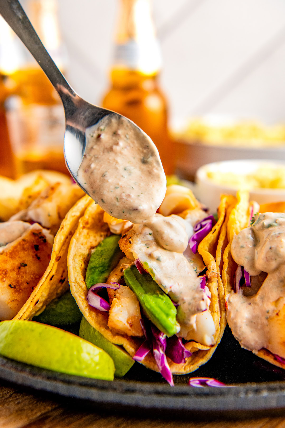 Adding creamy chipotle sauce to some tacos. 