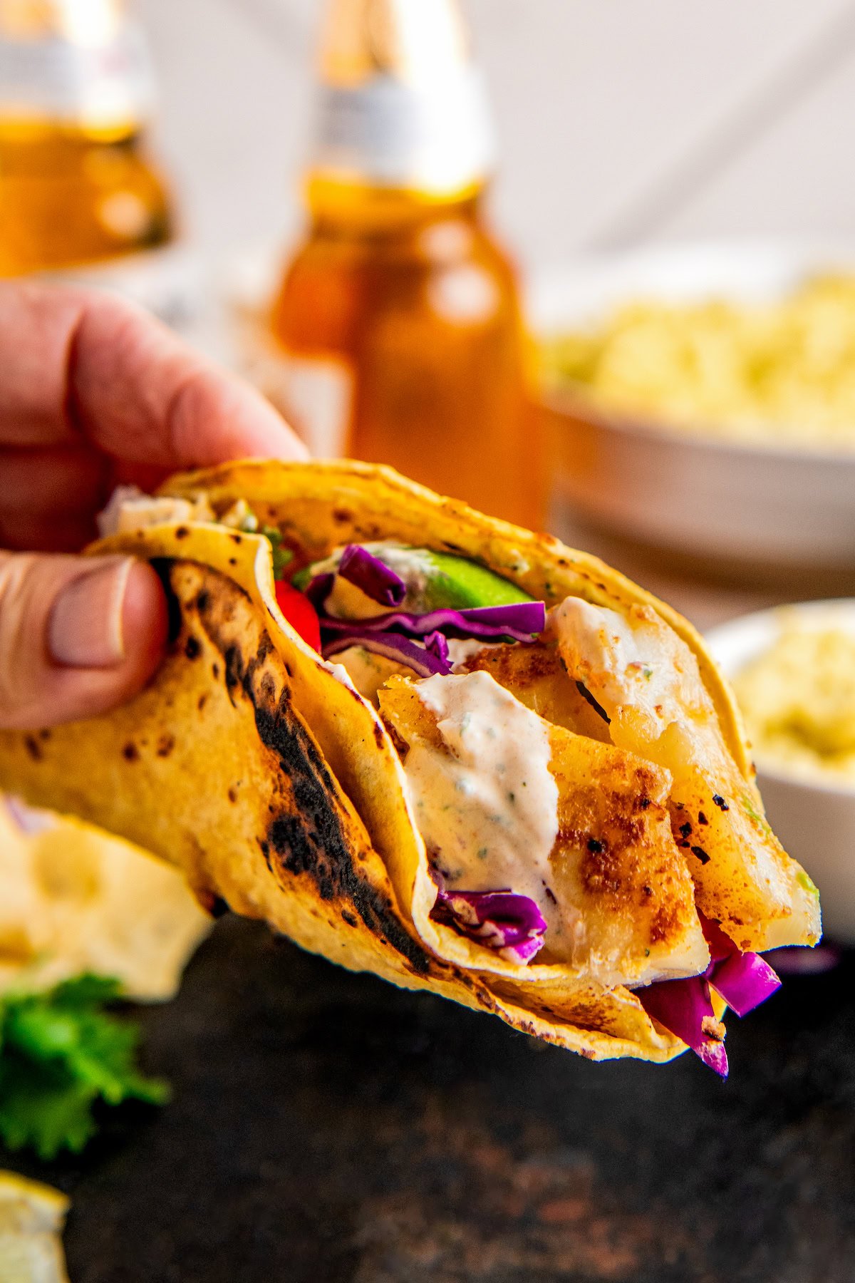 Grabbing a taco with crunchy veggie toppings and creamy fish taco sauce. 