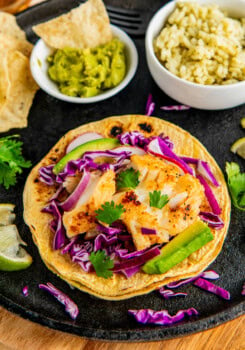 Fish tacos with purple cabbage, fresh cilantro, and avocado.