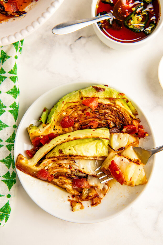 Plate of pan-friend cabbage with bacon and hot honey on the side.