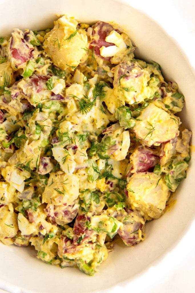 Red potato salad with dressing in a bowl.