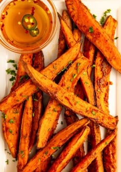 A bunch of garlicky air fryer sweet potato wedges with hot honey on the side.