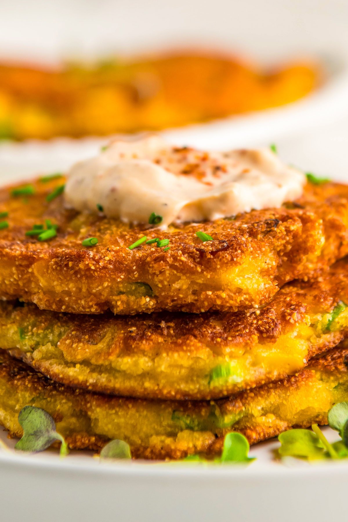 Stacked corn fritters with creamy Tajin sauce on top.