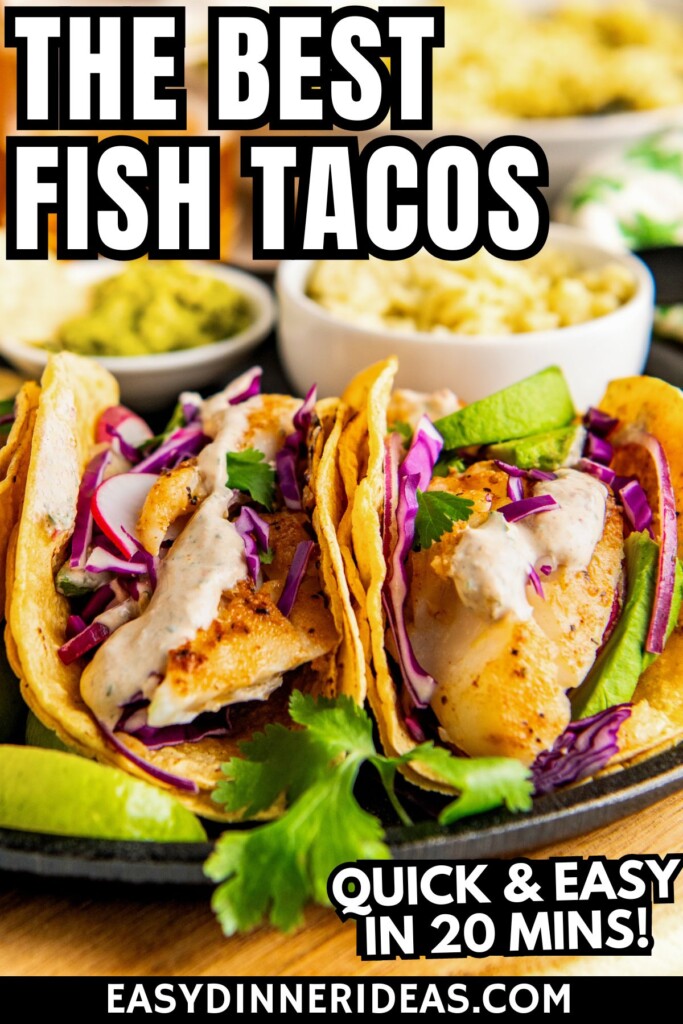 Two easy fish tacos with creamy fish taco sauce on a plate with all the toppings piled on top.
