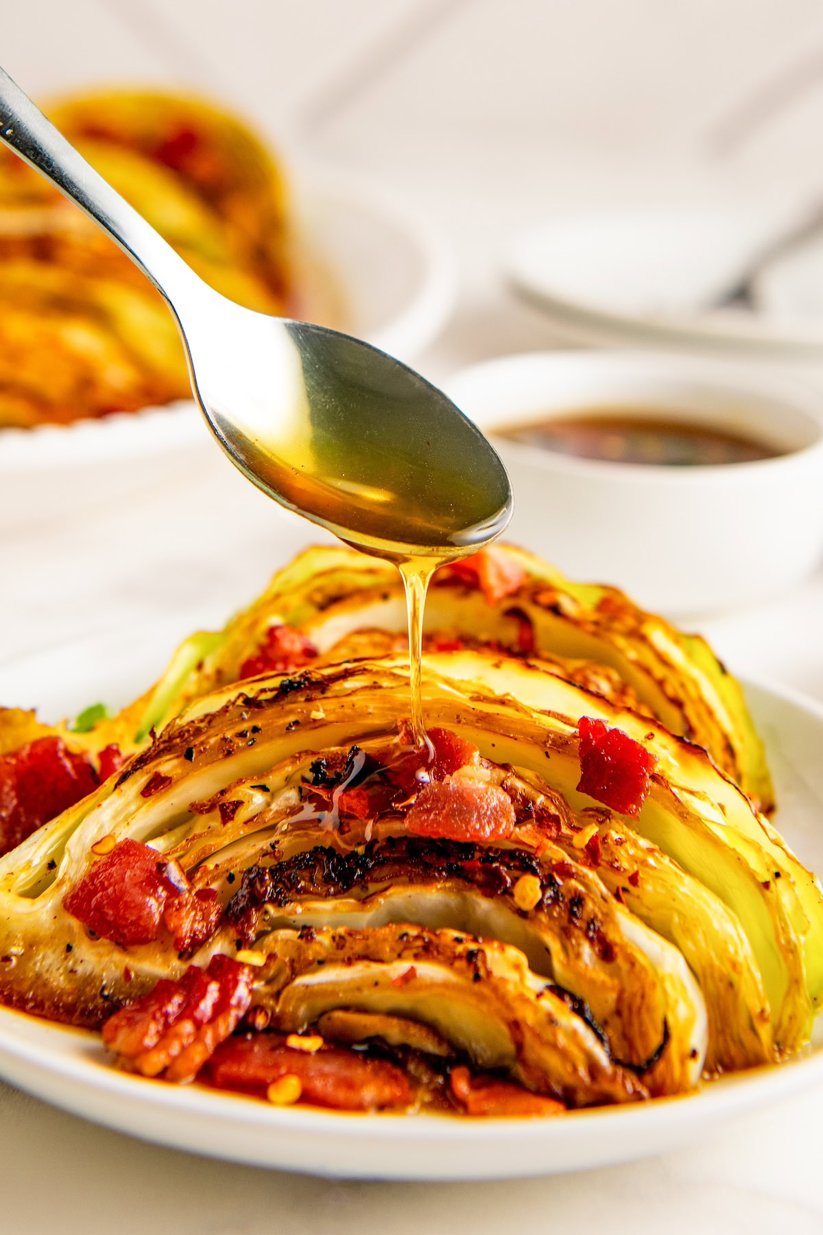 Southern fried cabbage with bacon on a plate with a spoon drizzling hot honey on top for serving.